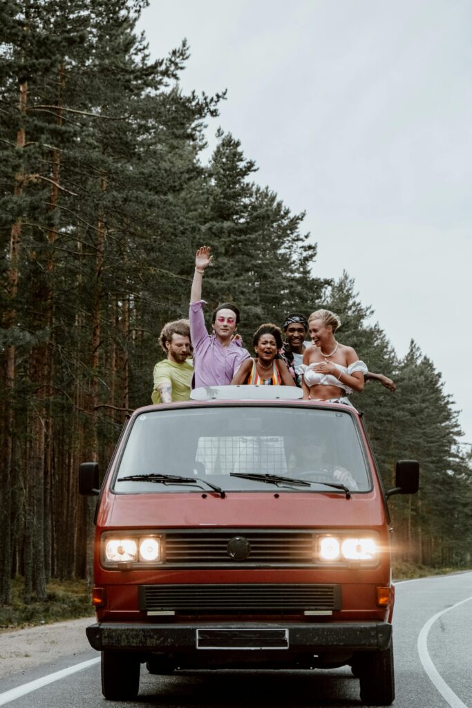 Group of friends having fun on a road trip in a vintage red van.